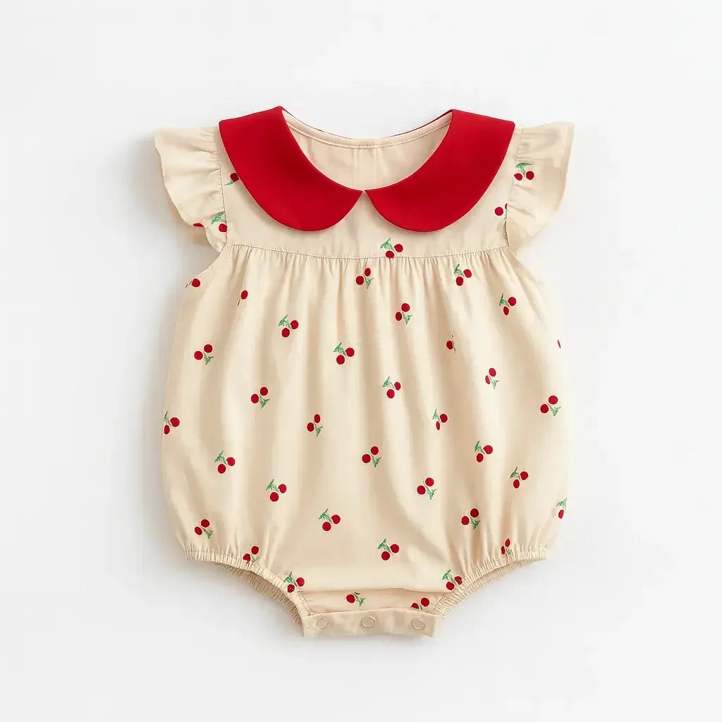 Body infantil feminino bege com estampa de cerejinhas vermelhas, gola peter pan vermelha e mangas curtas com babados.