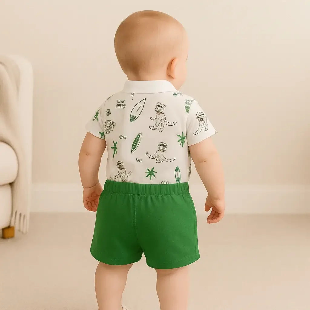 Bebê menino sorridente vestindo conjunto Dino Baby, macacão polo branco com estampa de dinossauro e palmeiras e short verde de algodão, ideal para verão - Baby Hello