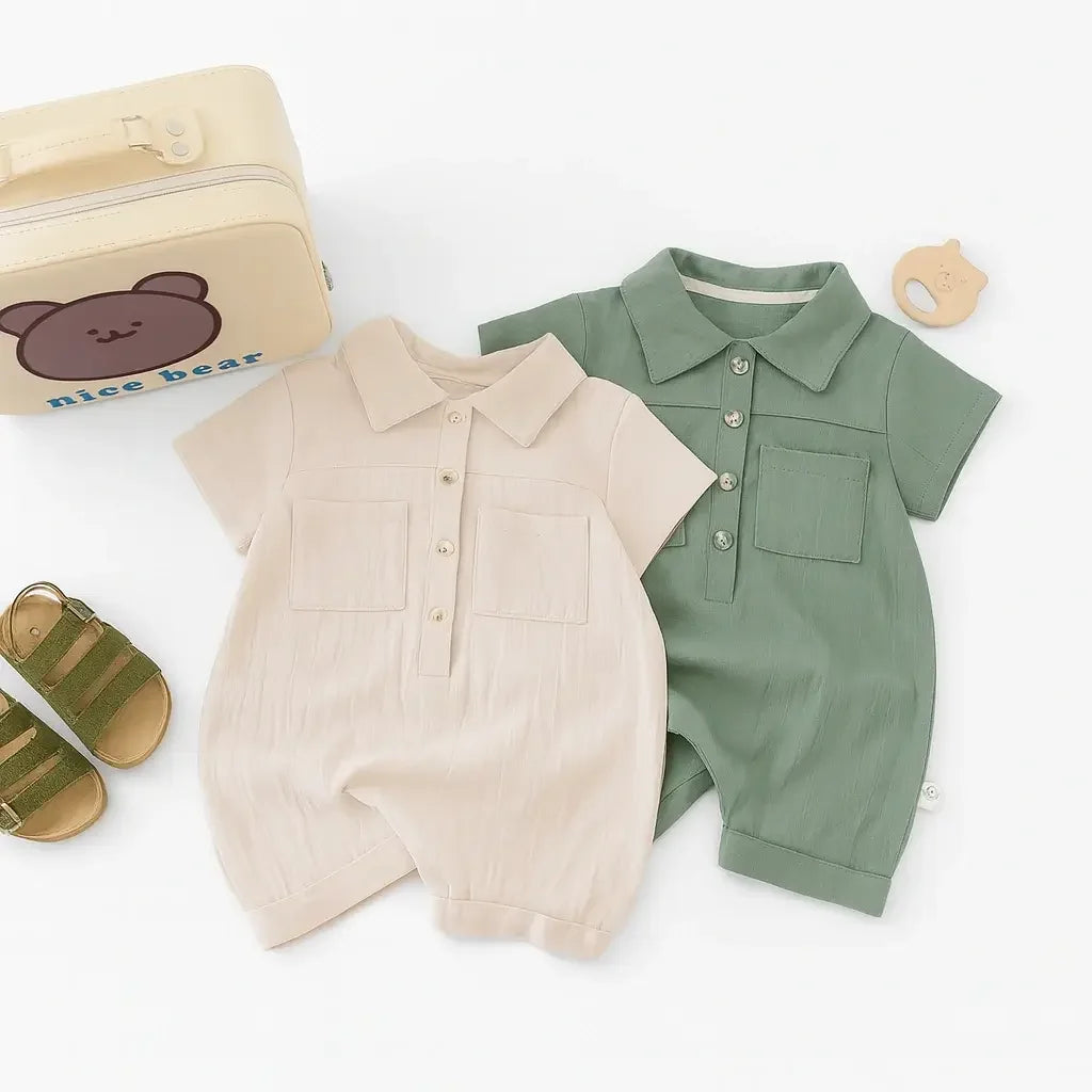 Macacão bebê manga curta em algodão, cores bege e verde, com botões frontais e bolso, acompanhado de sandália e acessórios.