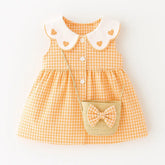 Vestido infantil xadrez laranja com gola branca de corações, botões frontais e bolsinha de palha com laço.