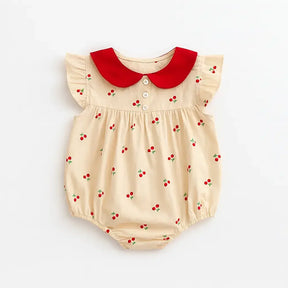 Body feminino para bebê bege com estampa de cerejinhas, gola peter pan vermelha, botões frontais e mangas curtas com babadinhos.