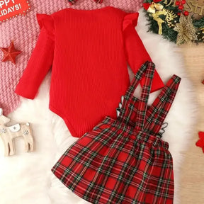 Conjunto infantil feminino composto por body vermelho canelado de manga longa com babadinhos nos ombros e jardineira xadrez vermelha com alças e aplique de rena com laço. A peça está disposta sobre fundo branco, com destaque para o visual natalino e delicado.