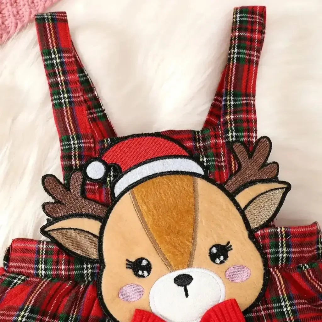 Conjunto infantil feminino composto por body vermelho canelado de manga longa com babadinhos nos ombros e jardineira xadrez vermelha com alças e aplique de rena com laço. A peça está disposta sobre fundo branco, com destaque para o visual natalino e delicado.