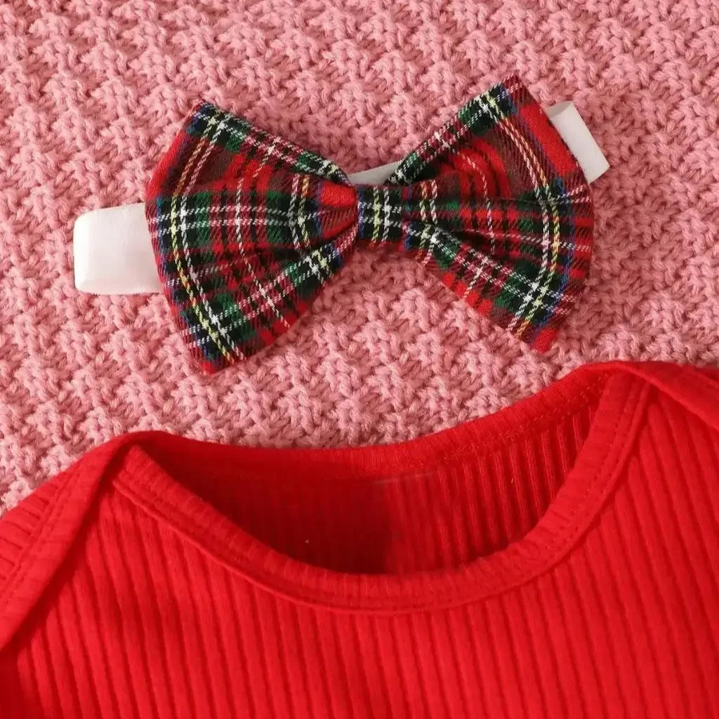 Conjunto infantil feminino composto por body vermelho canelado de manga longa com babadinhos nos ombros e jardineira xadrez vermelha com alças e aplique de rena com laço. A peça está disposta sobre fundo branco, com destaque para o visual natalino e delicado.
