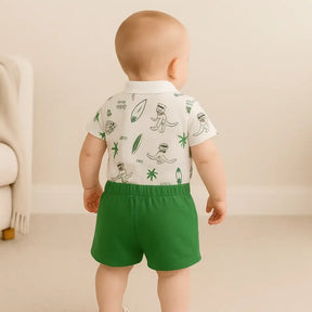 Bebê menino sorridente vestindo conjunto Dino Baby, macacão polo branco com estampa de dinossauro e palmeiras e short verde de algodão, ideal para verão - Baby Hello