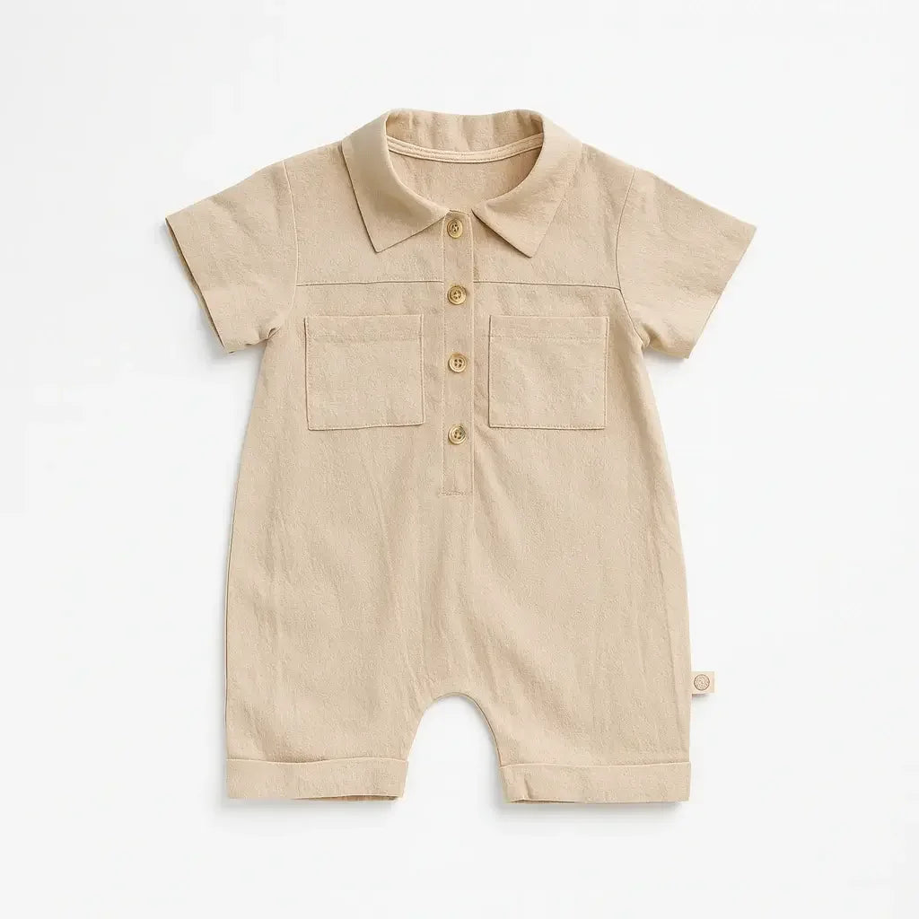 Macacão bebê manga curta em algodão, cor bege e com botões frontais e bolso.