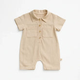 Macacão bebê manga curta em algodão, cor bege e com botões frontais e bolso.