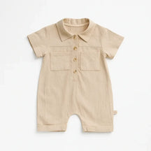 Macacão bebê manga curta em algodão, cor bege e com botões frontais e bolso.