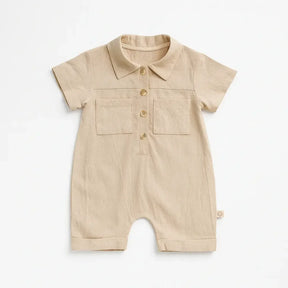 Macacão bebê manga curta em algodão, cor bege e com botões frontais e bolso.