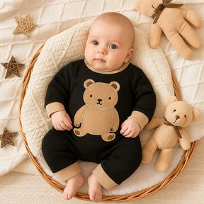 Bebê de 4 meses em cesta aconchegante, usando macacão preto com ursinho bege – moda infantil Baby Hello
