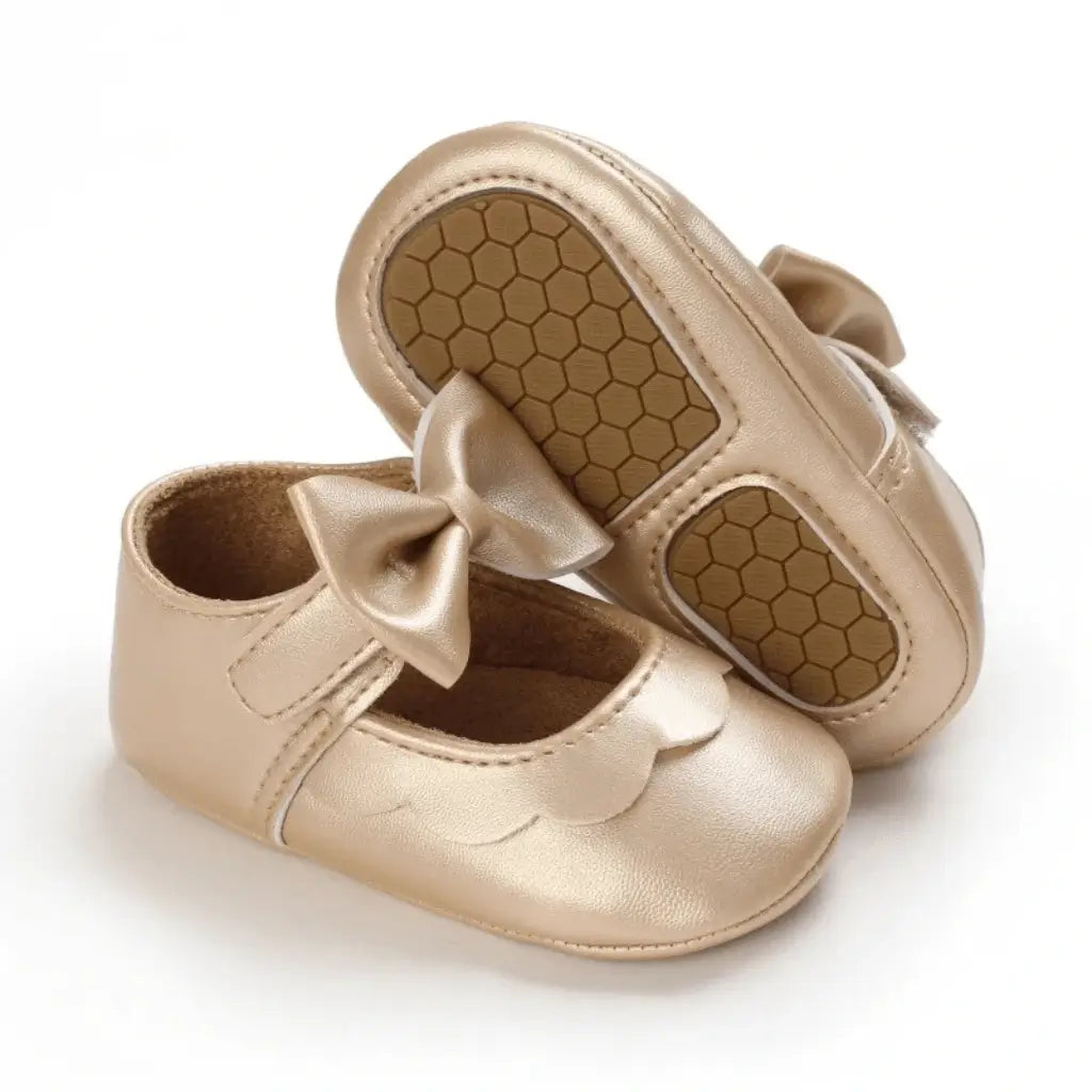 Sapato para bebê menina dourado, com laço delicado e sola macia antiderrapante, exibido em fundo branco para destaque do produto.