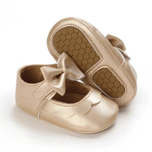 Sapato para bebê menina dourado, com laço delicado e sola macia antiderrapante, exibido em fundo branco para destaque do produto.