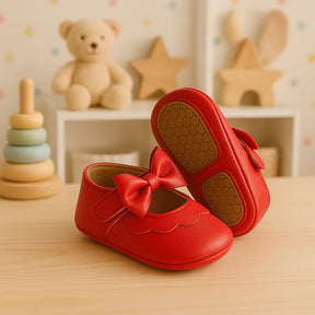 Sapatinho vermelho de bebê com laço e sola antiderrapante, exposto em cenário aconchegante de quarto infantil.